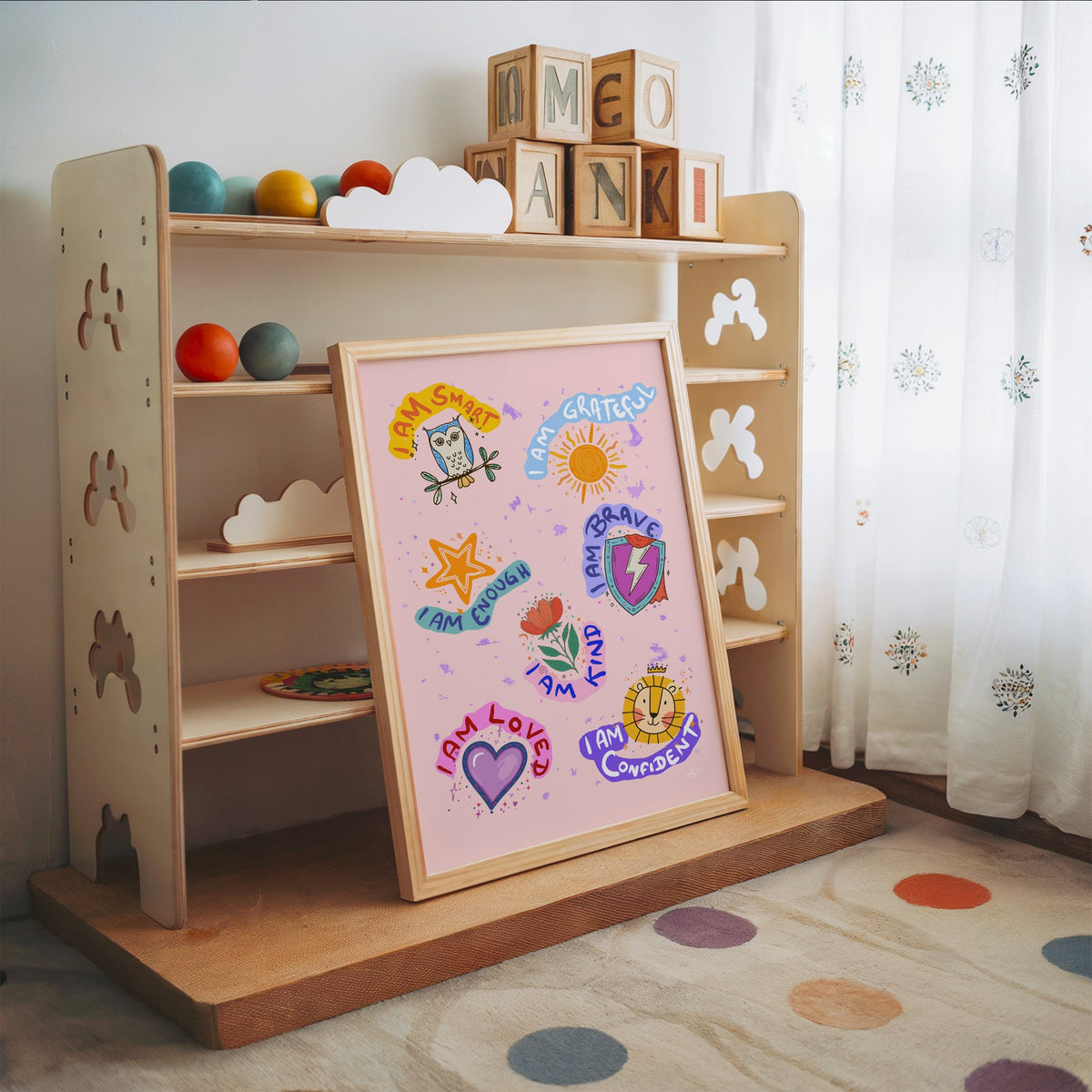 I am affirmations sticker nursery print in an oak frame leaning on a toy shelf with wooden letter blocks