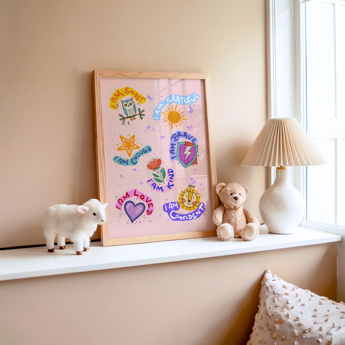 I am affirmations sticker nursery print in an oak frame on a window ledge with a toy lamb and teddy