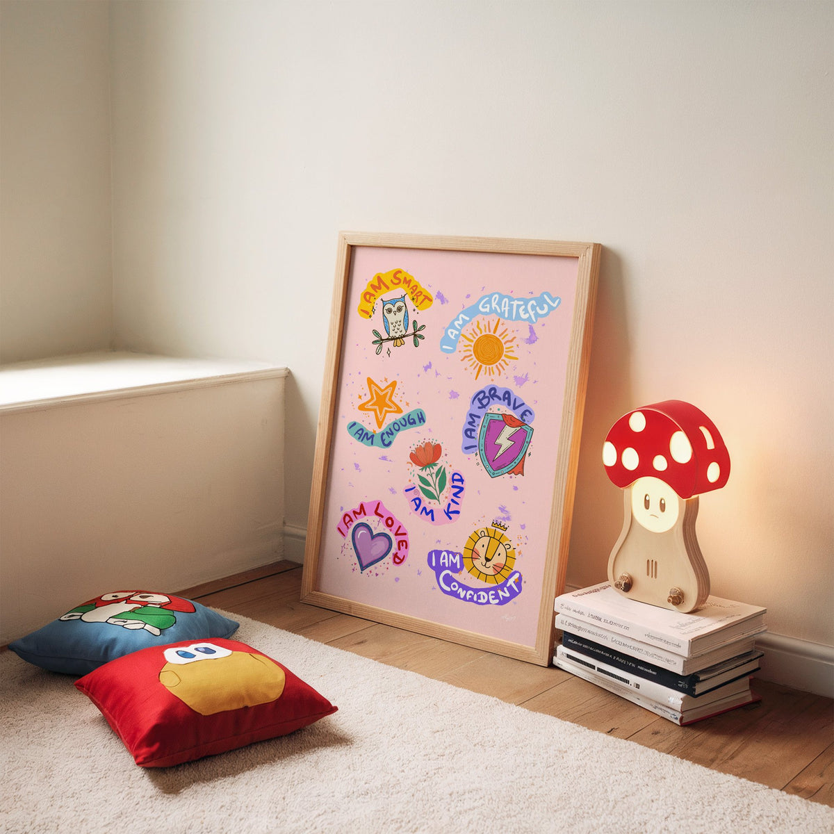 I am affirmations sticker nursery print in an oak frame leaning on a rug beside a mushroom lamp and floor cushions