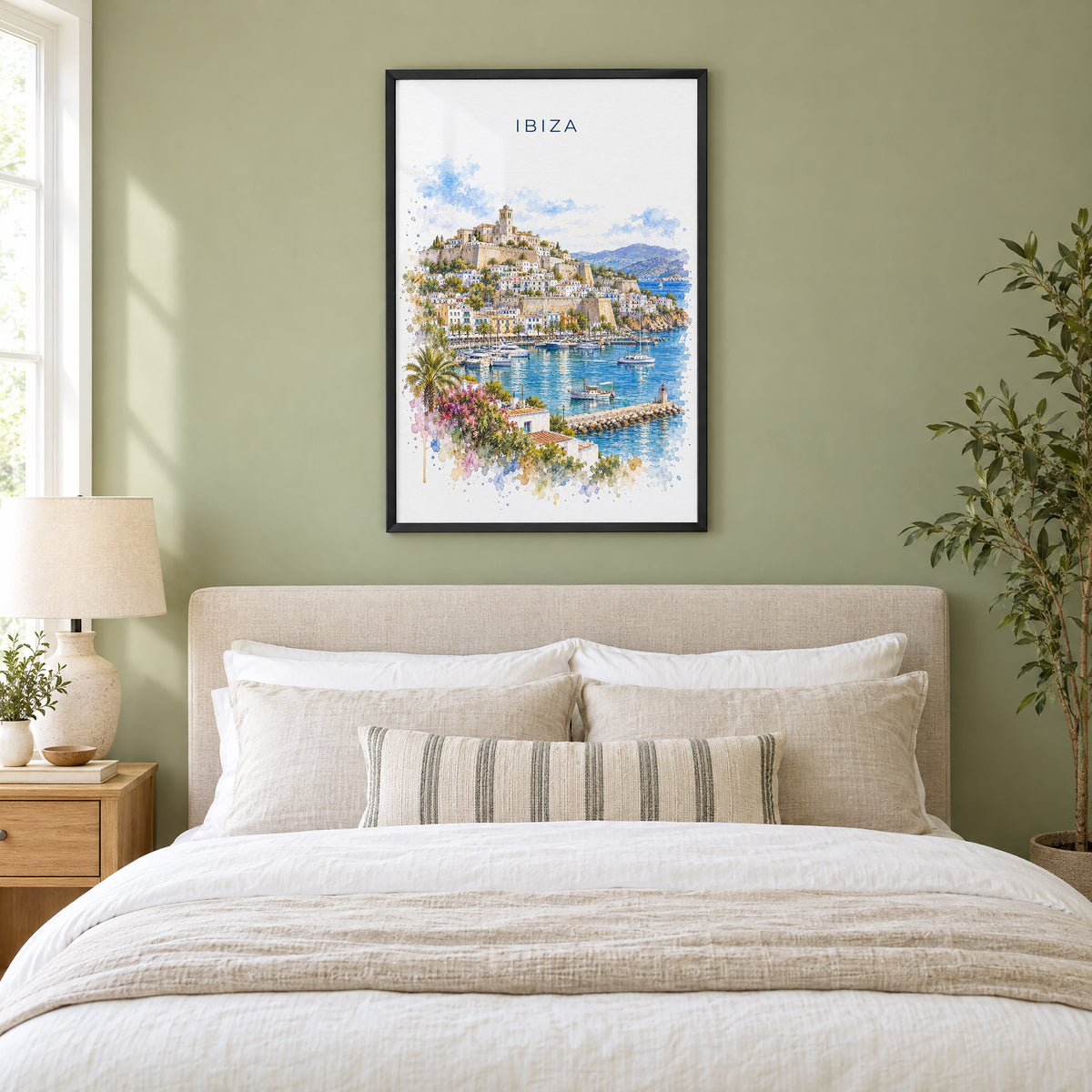 Ibiza watercolor print in a black frame above an upholstered headboard in a sage green bedroom
