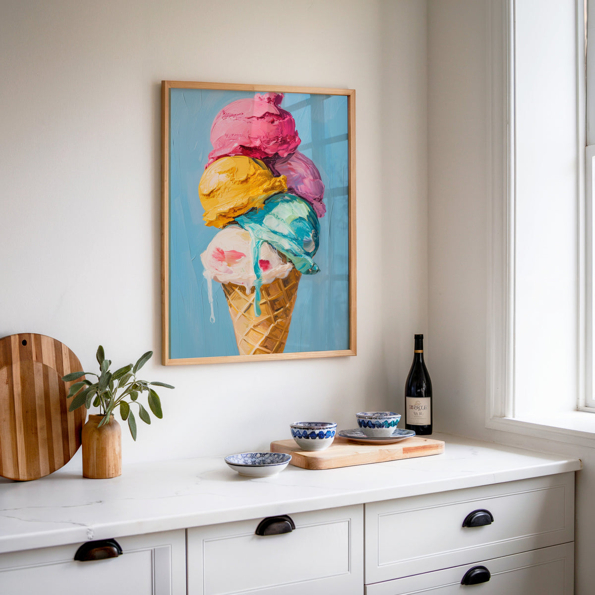 Ice cream cone print in an oak frame above a white sideboard with a bottle of wine