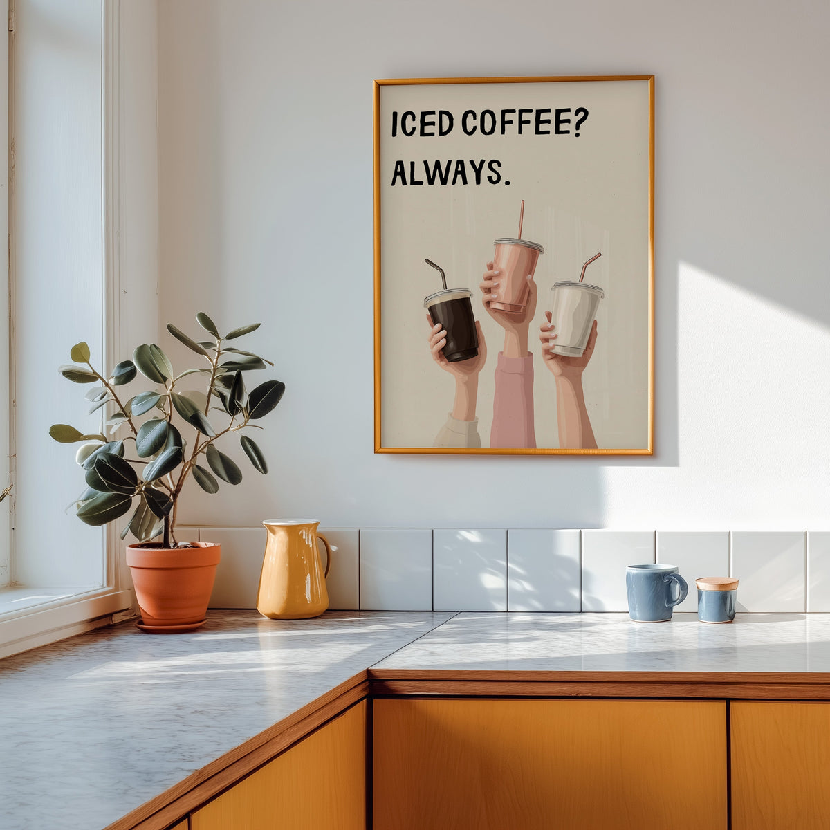 Iced Coffee Always print shown in a gold frame above a marble counter in a tan kitchen