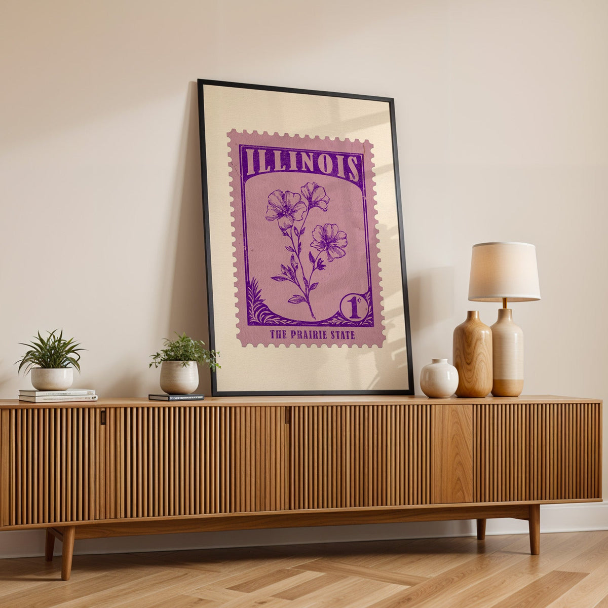 Illinois state flower print in a black frame leaning on a fluted wood credenza with vases and a lamp