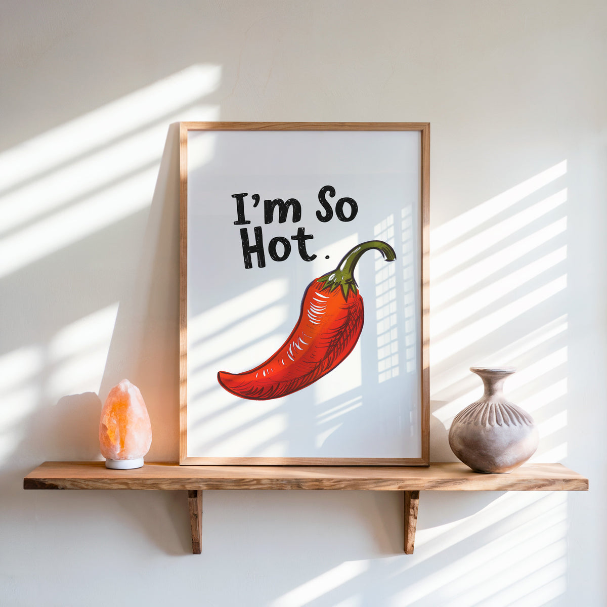 I'm So Hot chilli print in an oak frame on a live-edge shelf beside a salt lamp