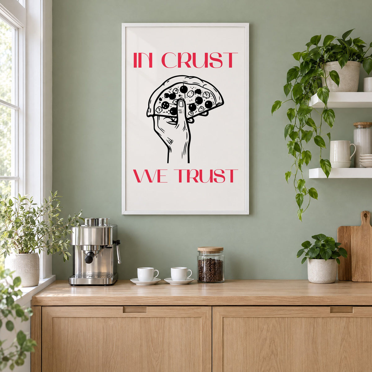 In Crust We Trust pizza print in a white frame on a sage green coffee nook wall above an espresso machine