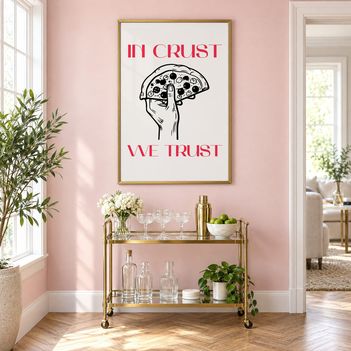 In Crust We Trust pizza print in a brass frame above a gold bar cart on a blush pink wall