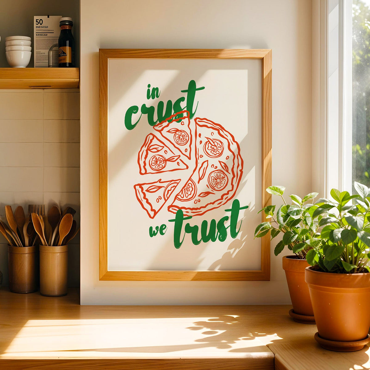 Italian pizza print in a light wood frame on a butcher block counter by crocks of wooden utensils