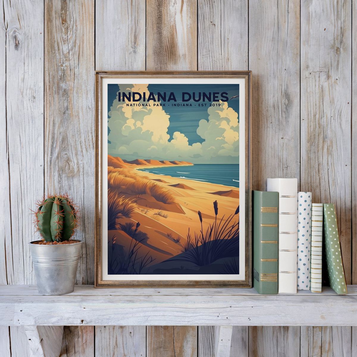 Indiana Dunes poster in an antique gold frame against whitewashed farmhouse planks beside books and a cactus
