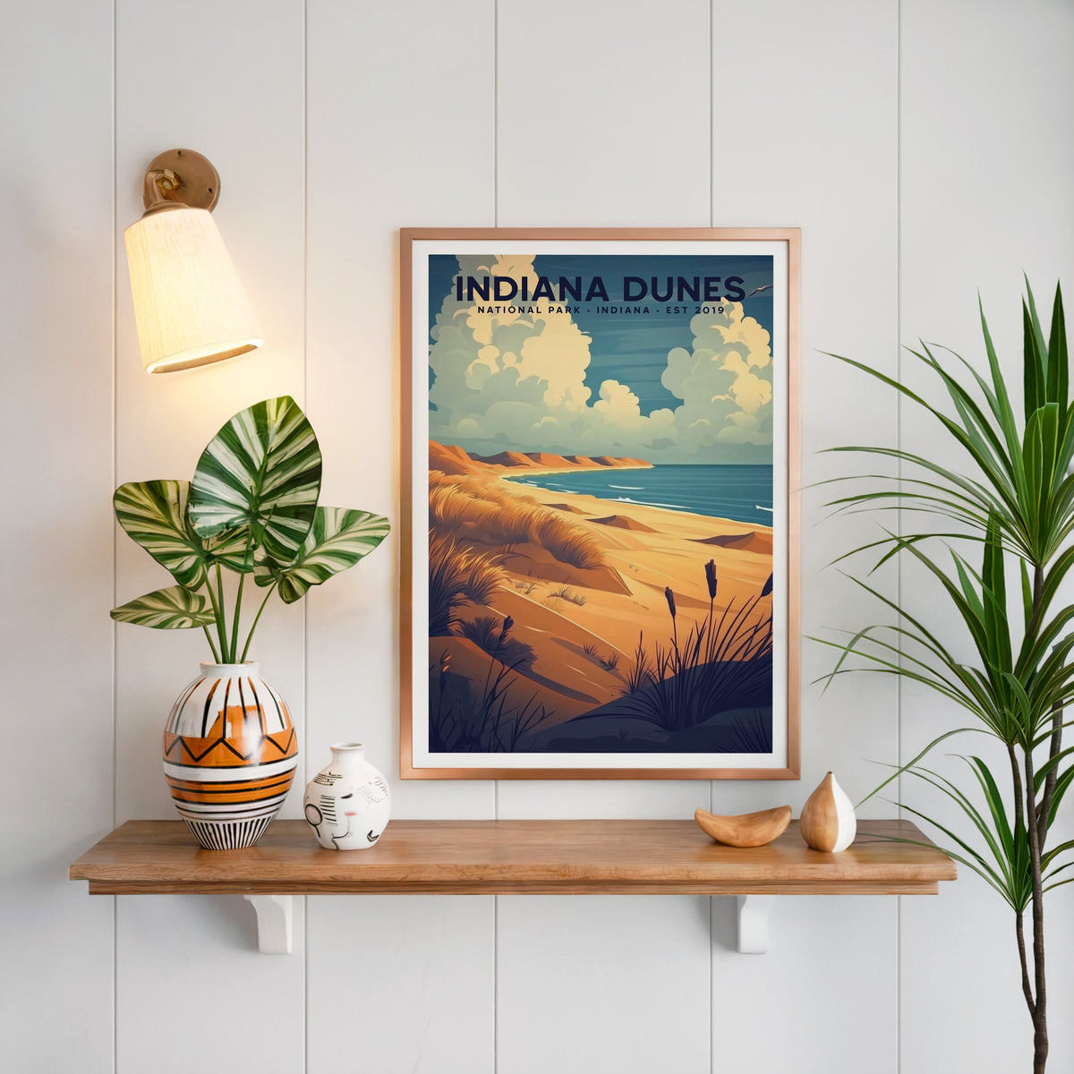 Indiana Dunes National Park print in a copper frame above an oak shelf on white shiplap with a brass sconce