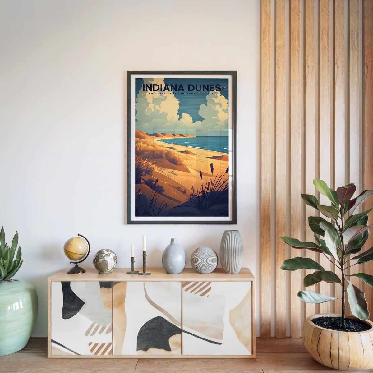 Indiana Dunes National Park print in a black frame above a light wood sideboard with a globe and ceramic vases