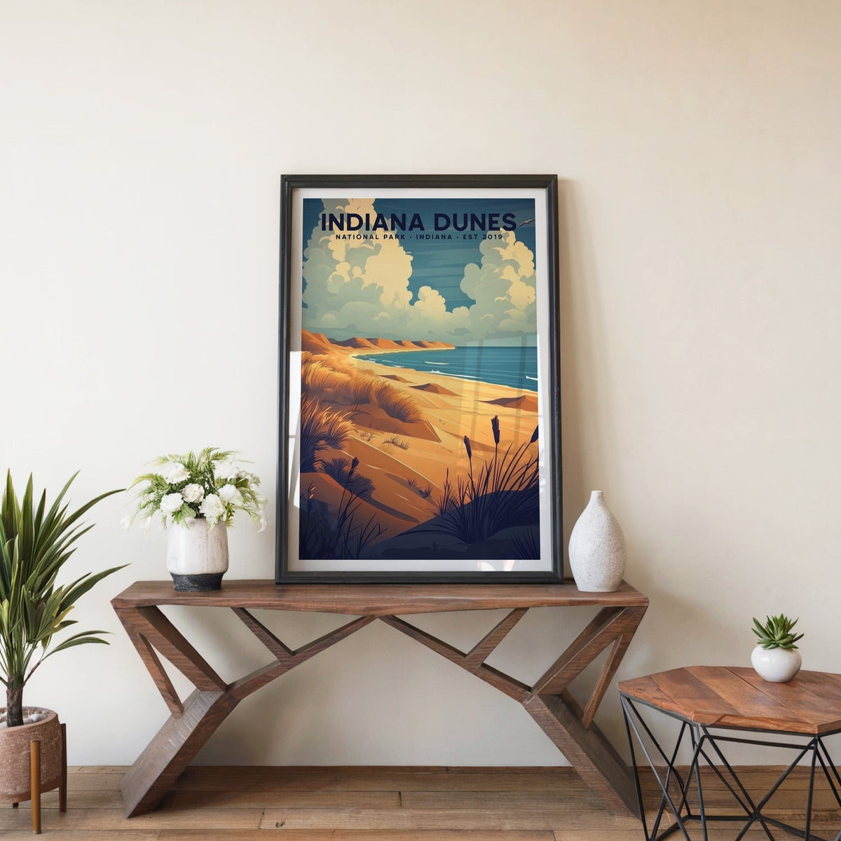 Indiana Dunes poster in a black frame on an entryway console table beside white flowers and a yucca