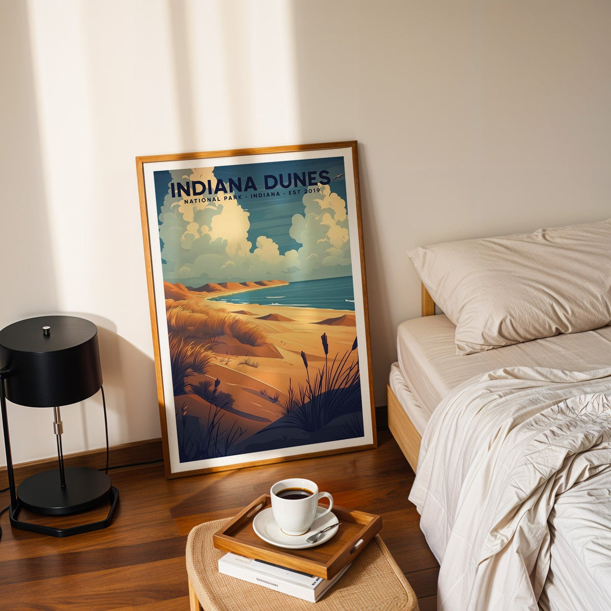 Indiana Dunes National Park print in an oak frame leaning on a bedroom floor beside the bed and a coffee tray