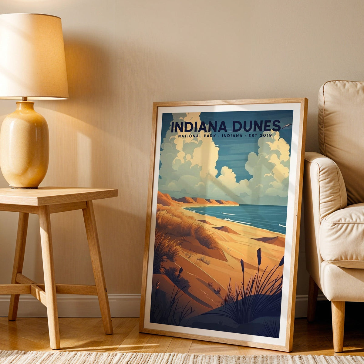 Indiana Dunes print in an oak frame beside a cream armchair and an amber lamp in warm afternoon light