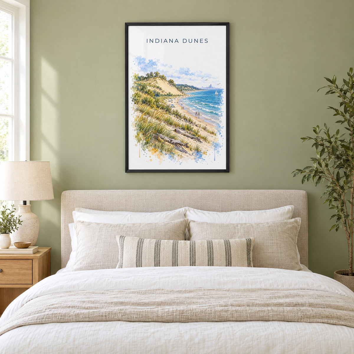 Indiana Dunes National Park watercolor print in a black frame above an upholstered headboard in a sage green bedroom