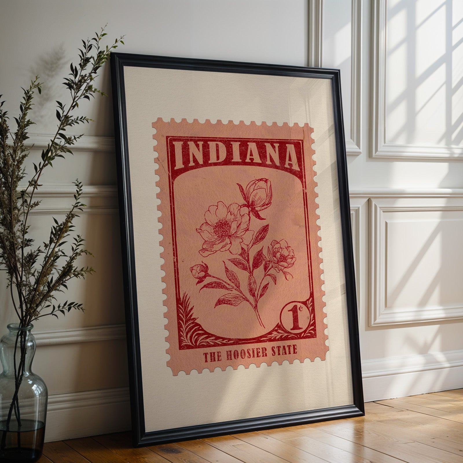 Indiana state flower print in a black frame leaning against a white panelled wall beside olive branches