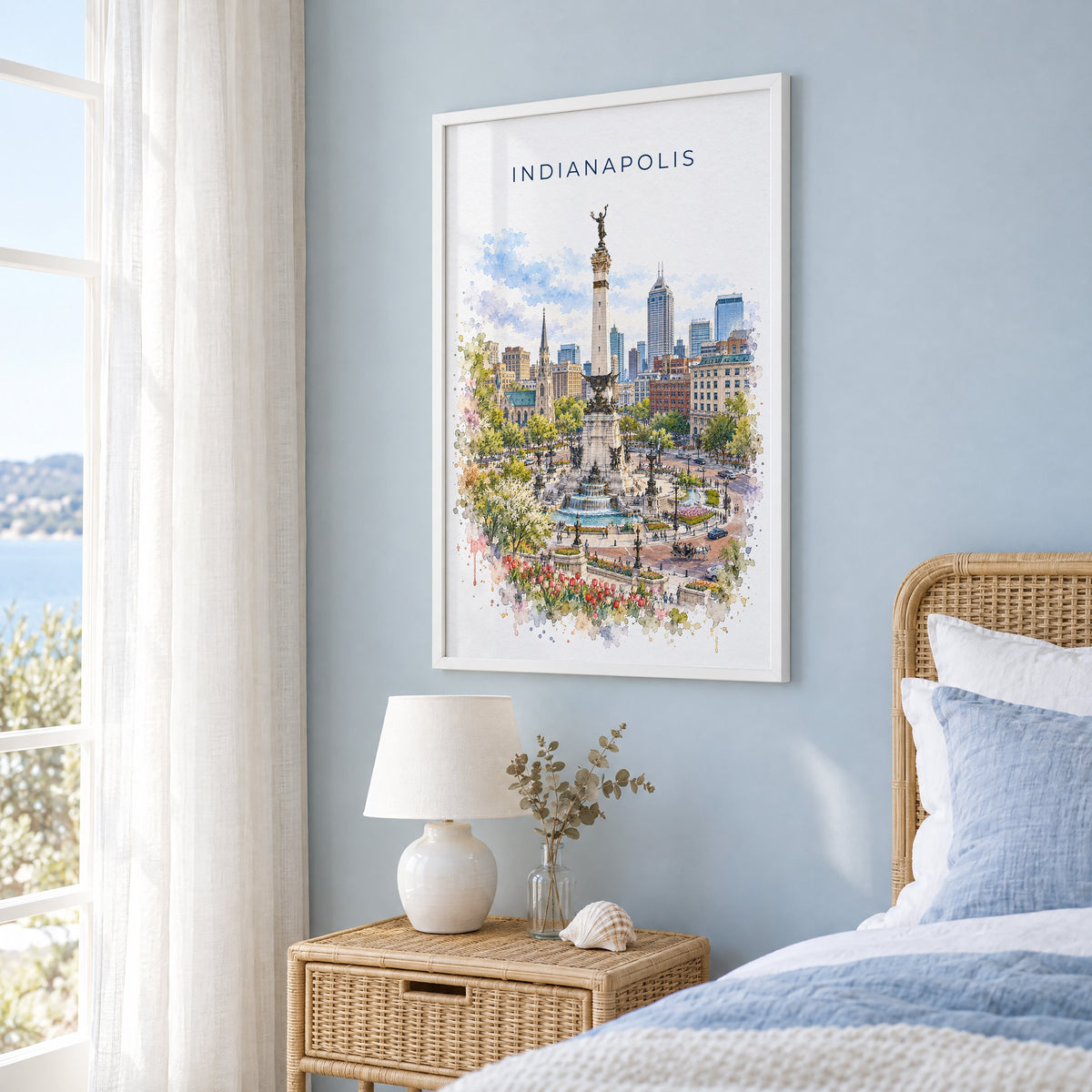 Indianapolis watercolor print in a white frame on a pale blue wall beside a rattan bed in a coastal bedroom