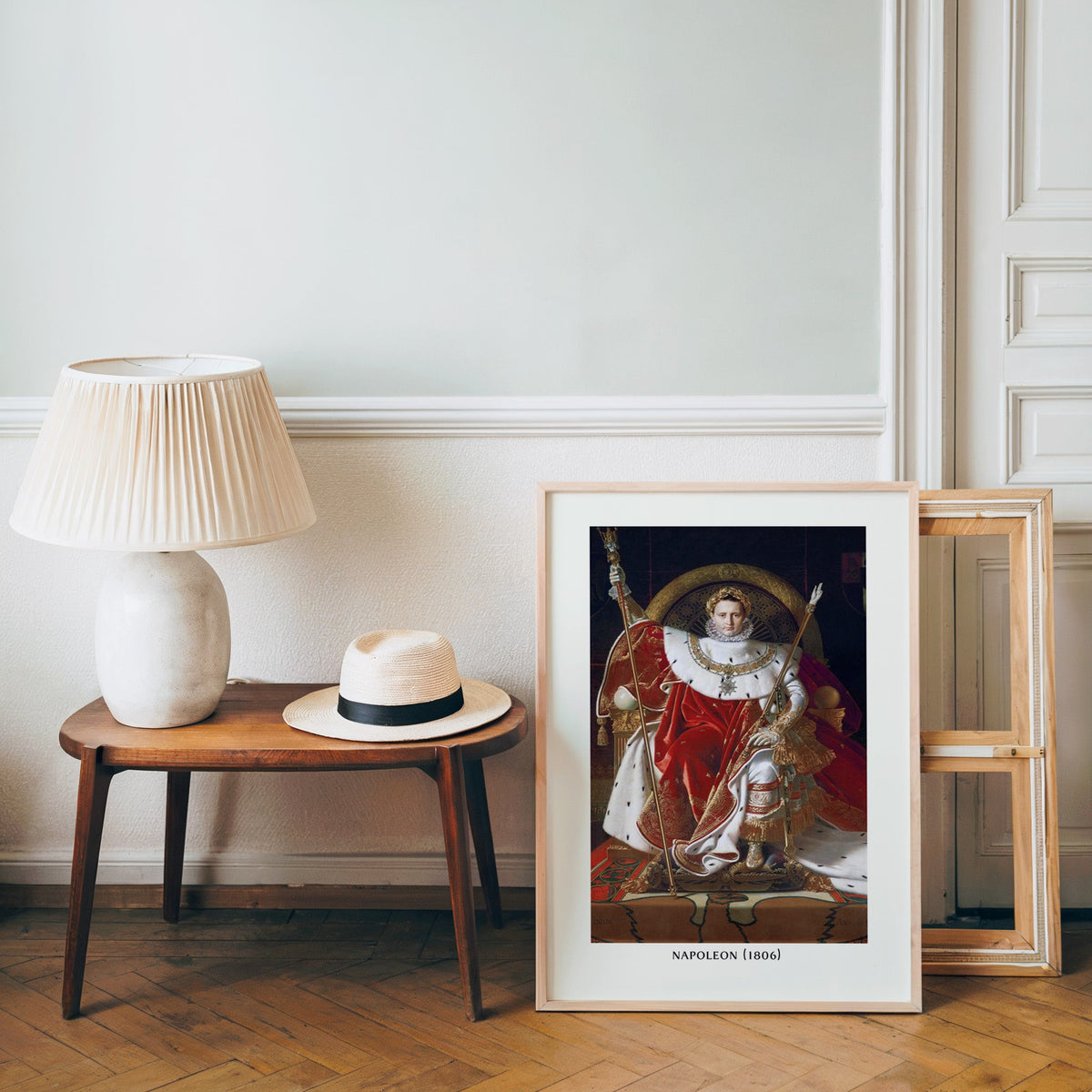 French neoclassical poster in a light wood frame leaning by a bench and hat