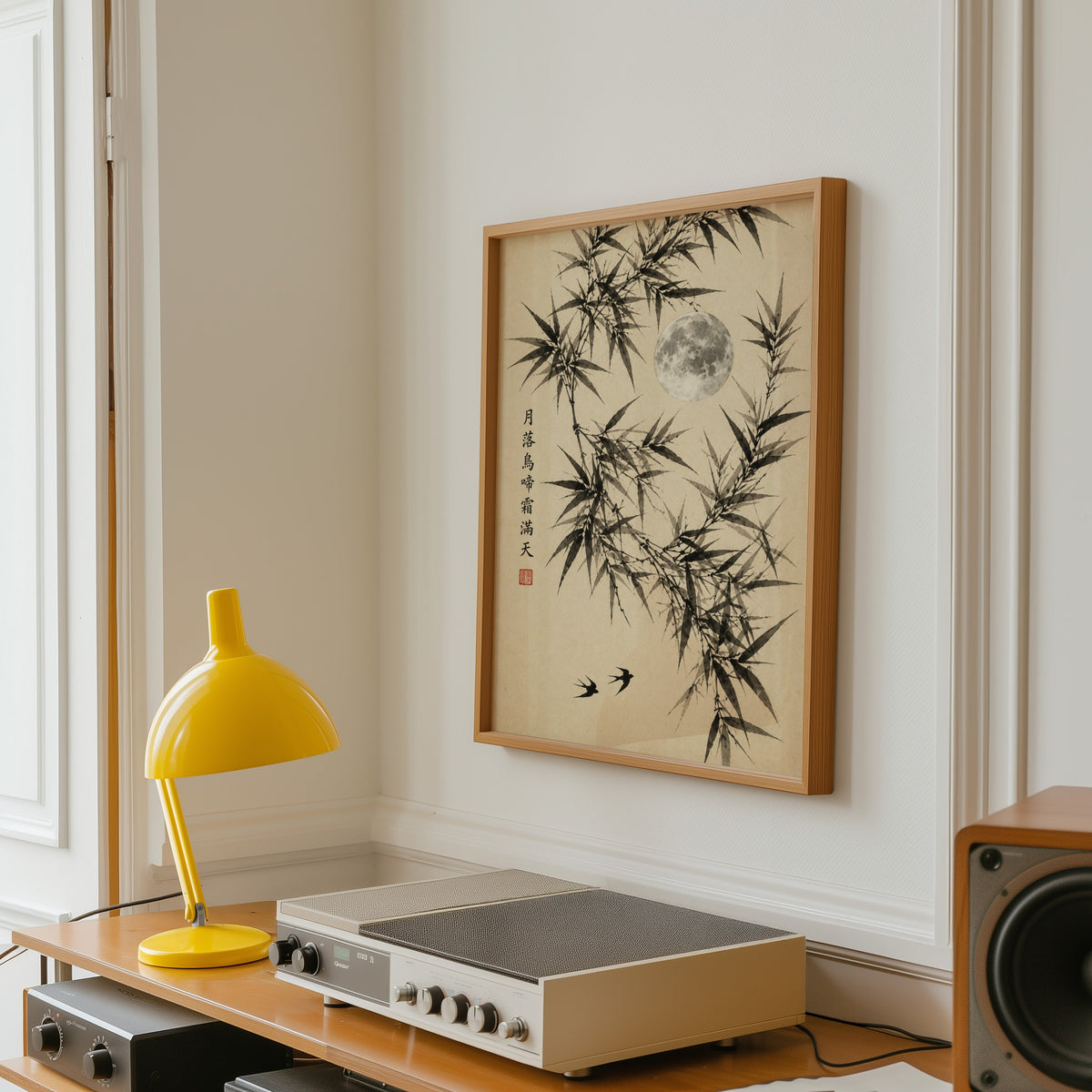 ink bamboo, full moon and swallows print in an oak frame above a vintage hi-fi shelf with a yellow desk lamp