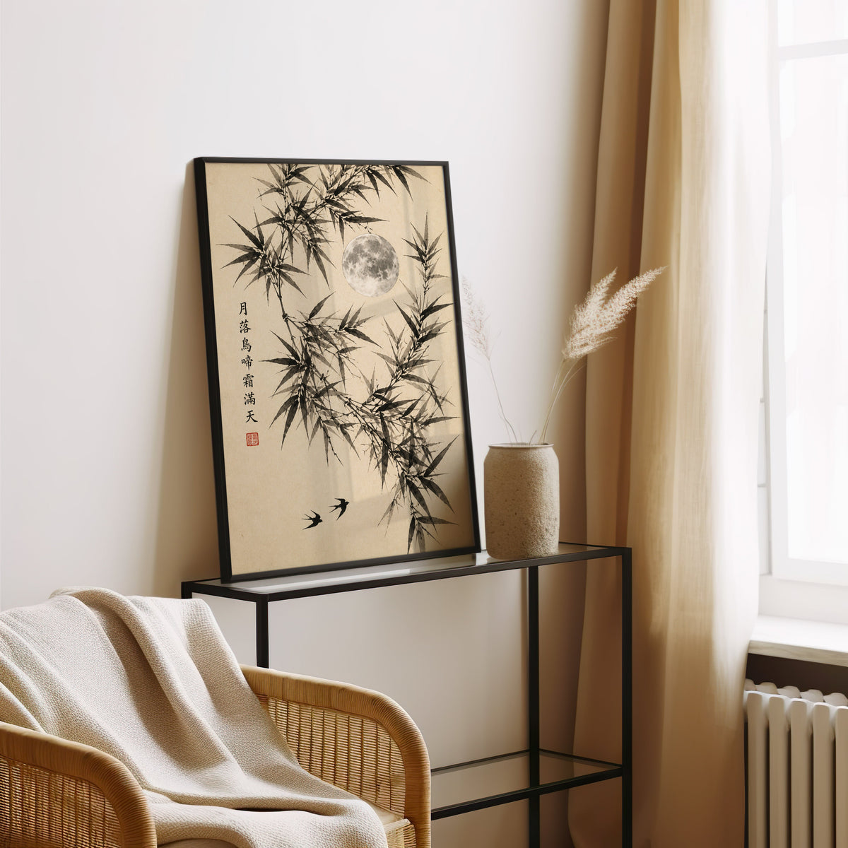 ink bamboo, full moon and swallows print in a black frame leaning on a glass console beside pampas grass