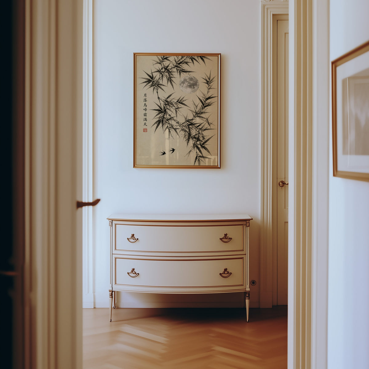 ink bamboo, full moon and swallows print shown in a gold frame in a hallway above a cream dresser