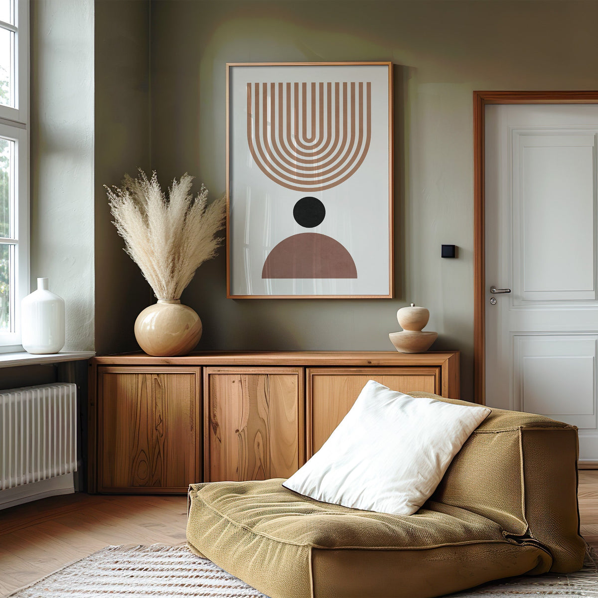 Inverted tan arch and mauve dome mid century print in an oak frame on an olive green wall above a wood sideboard with pampas