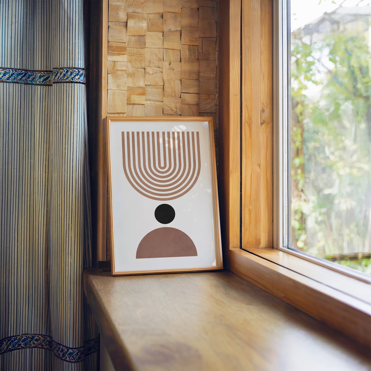 Inverted tan arch and mauve dome mid century print in a light wood frame leaning on a wooden window sill by a garden view