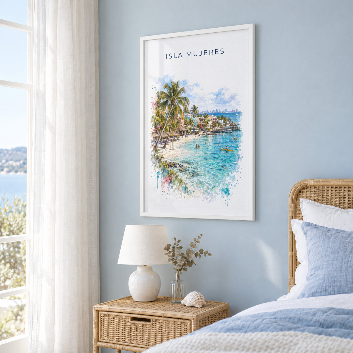 Isla Mujeres watercolor print in a white frame on a pale blue wall beside a rattan bed in a coastal bedroom