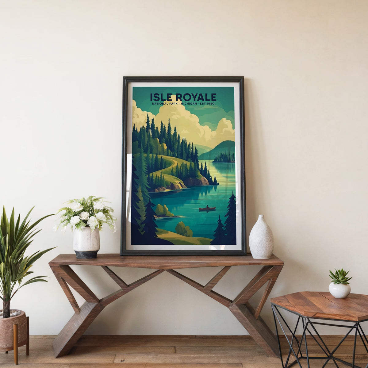 Isle Royale poster in a black frame on an entryway console table beside white flowers and a yucca