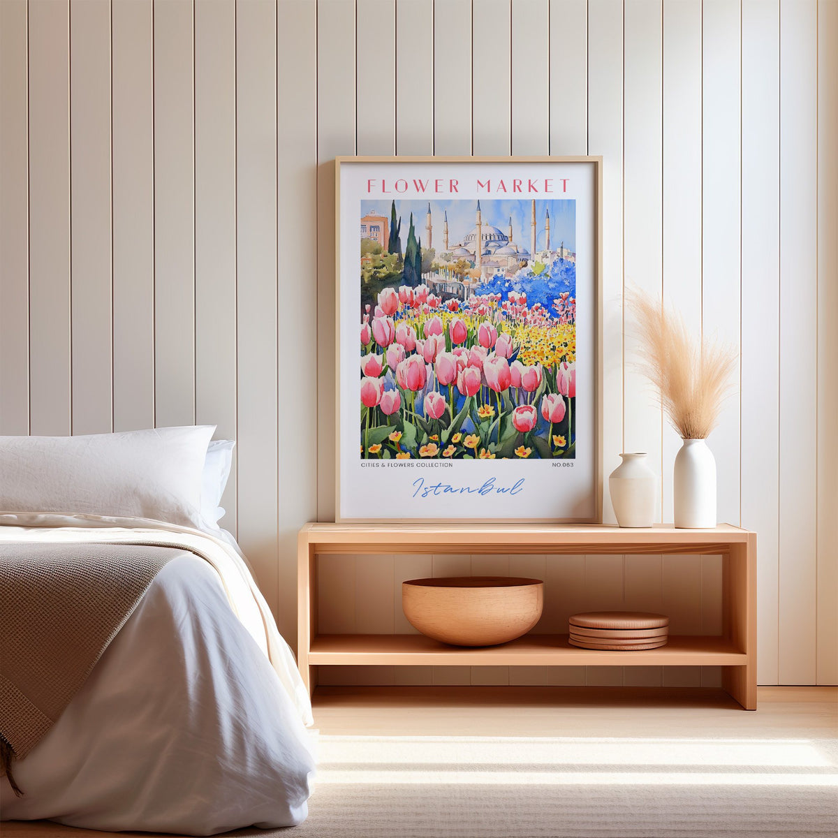 Istanbul flower market print in an oak frame on a wood bench against a white shiplap bedroom wall with pampas grass
