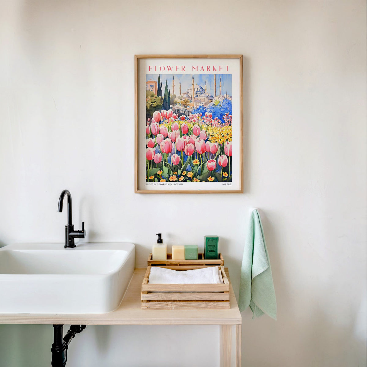 Istanbul flower market print in an oak frame above a white bathroom sink with folded towels