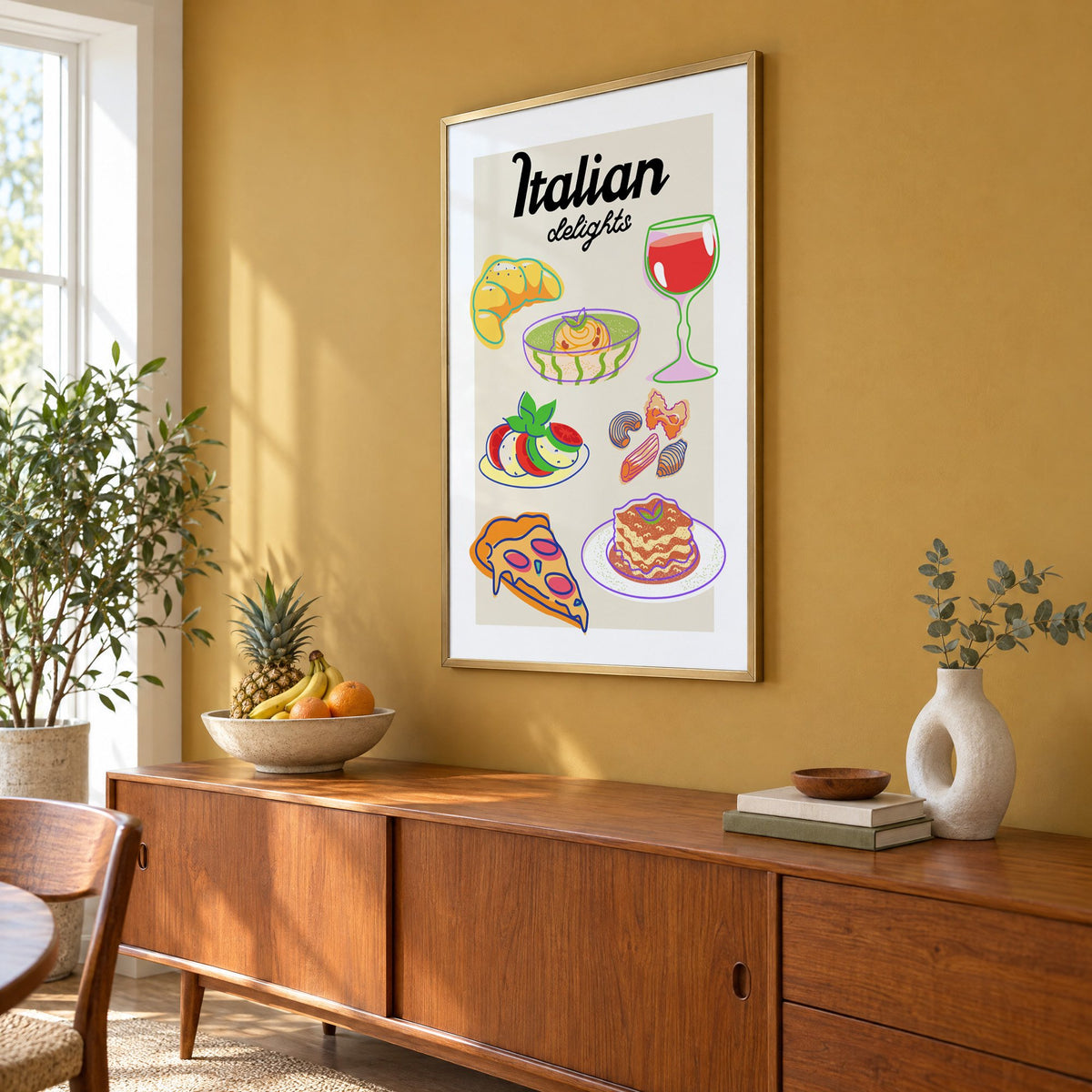 Italian delights colorful food doodle print in a brass frame on a mustard wall above a teak sideboard with a fruit bowl, seen at an angle