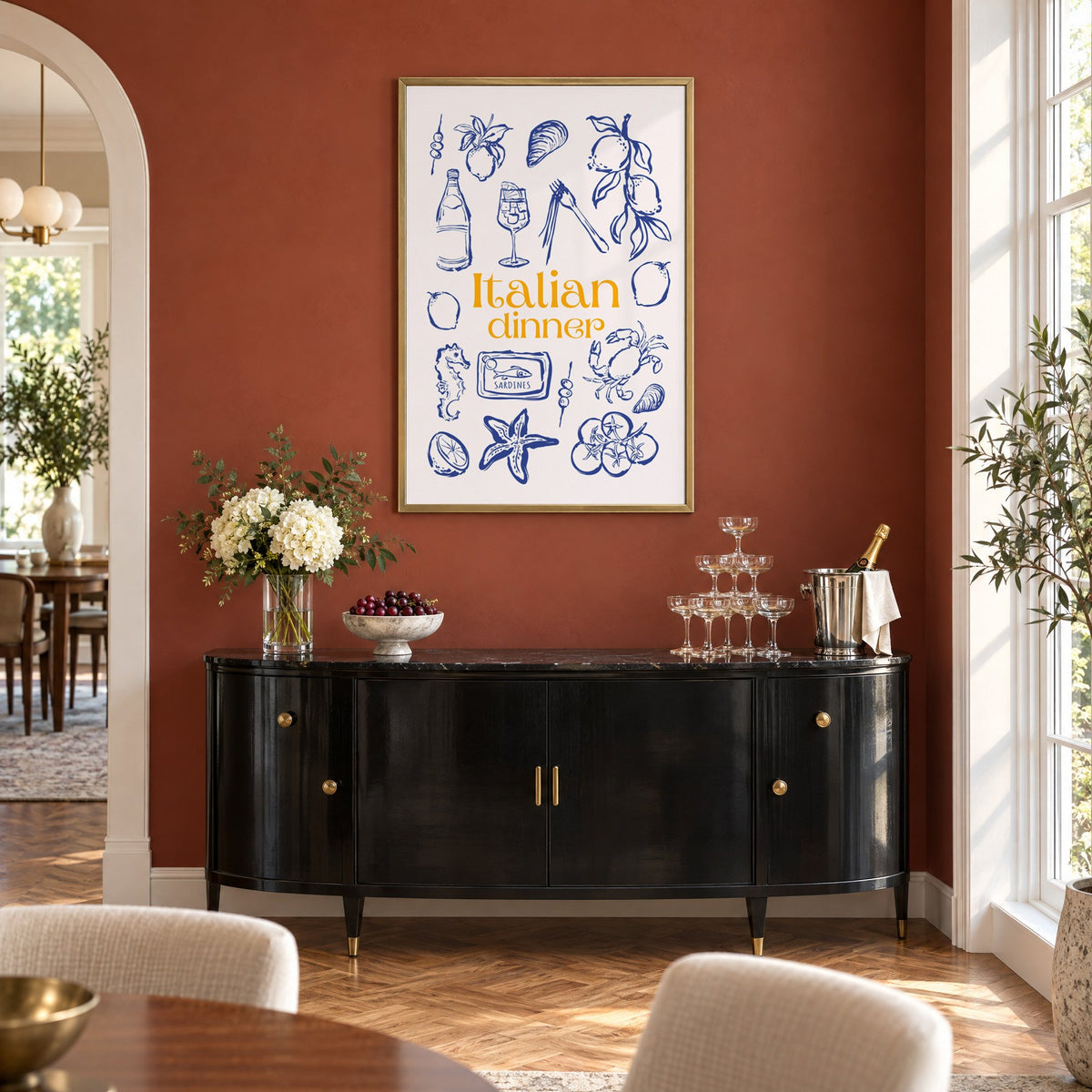Italian dinner blue doodle print in a brass frame on a terracotta wall above a black buffet with a champagne tower