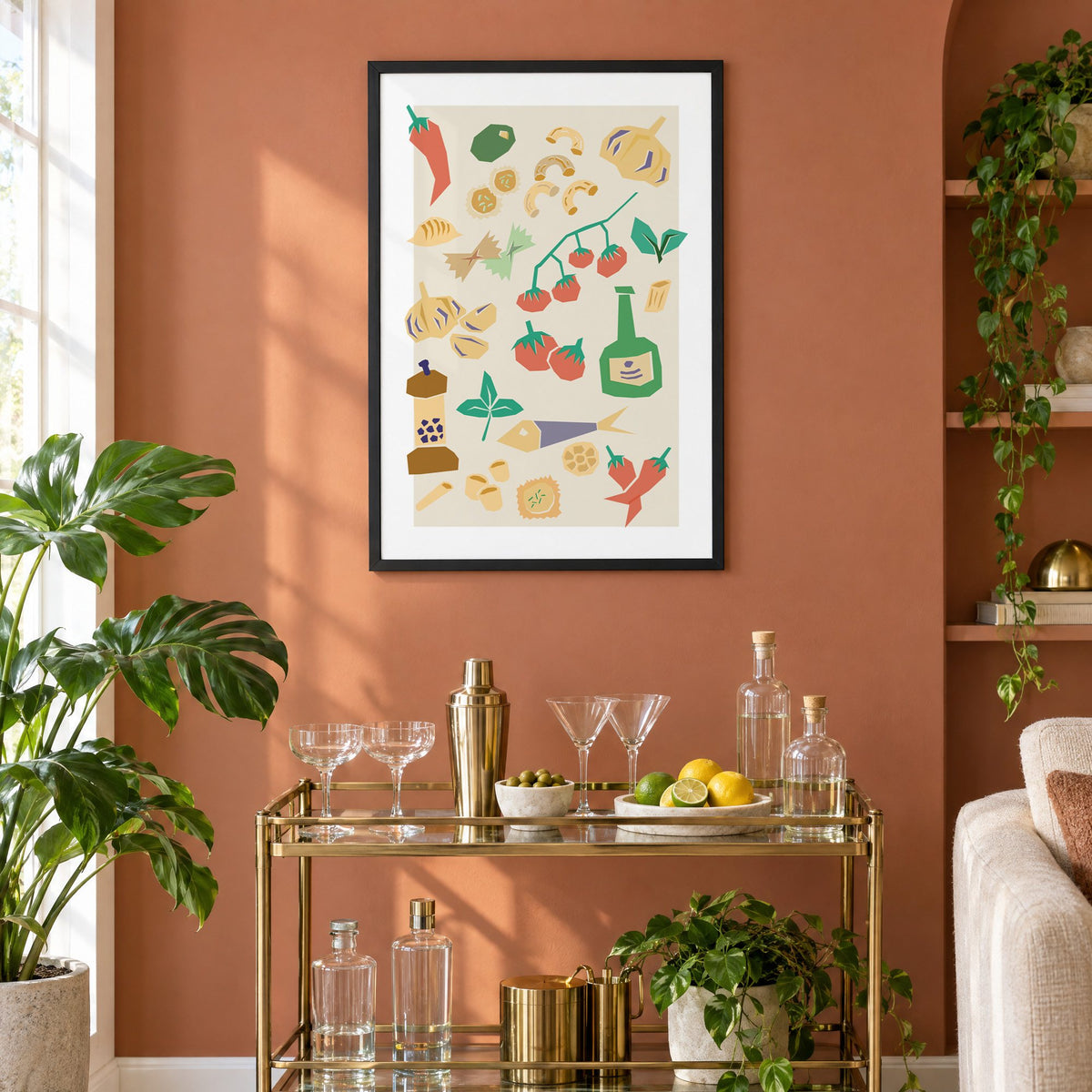 Italian ingredients cut-paper pattern print in a black frame on a terracotta wall above a brass bar cart with coupes and citrus