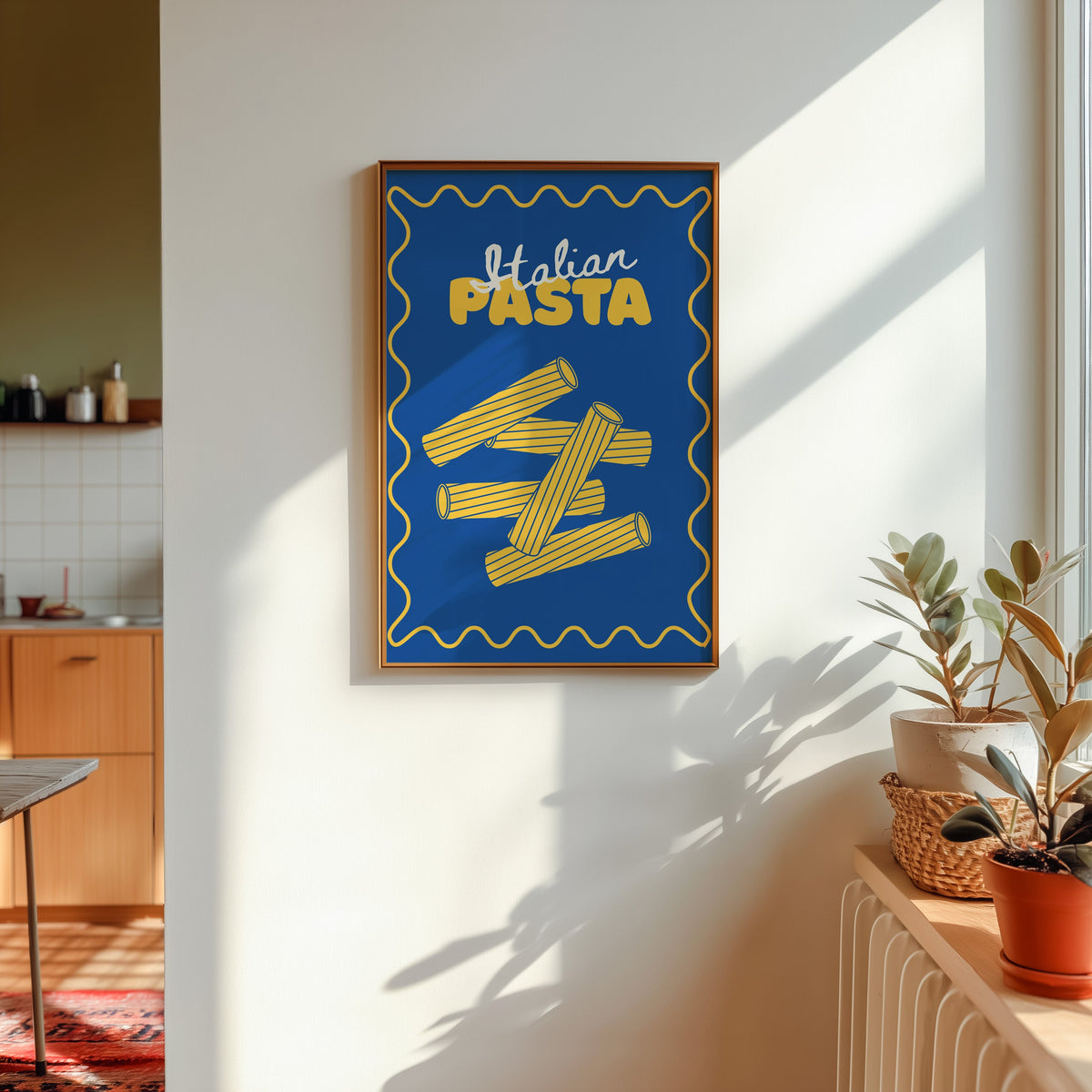 Navy rigatoni print in a gold frame in sunlight with plants and a kitchen beyond