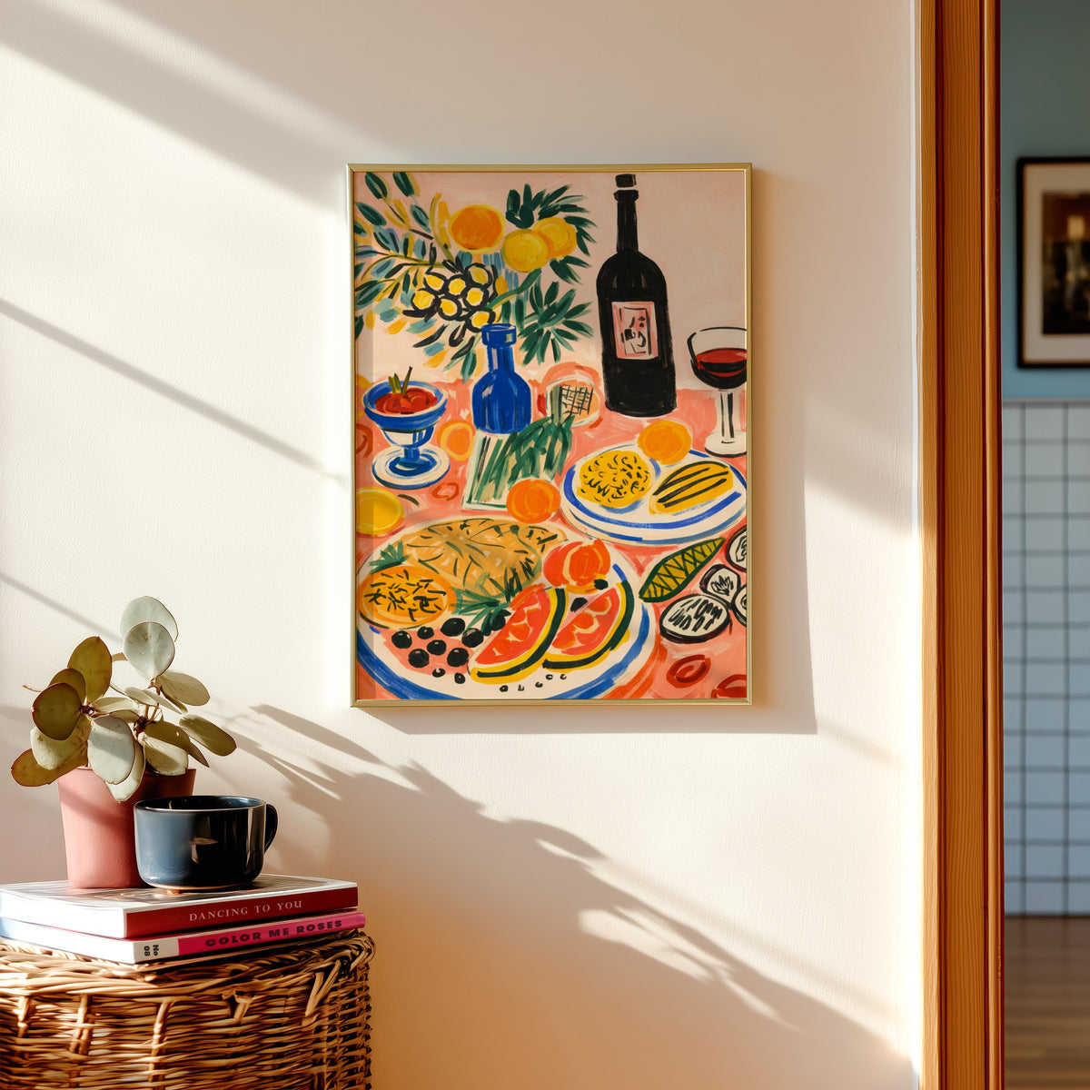 Italian table print in a gold frame above a basket of books and a pilea plant