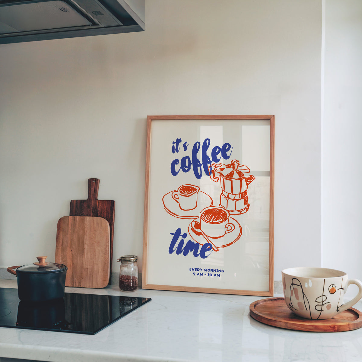 It's Coffee Time moka pot print in a light pine frame leaning on a marble kitchen counter