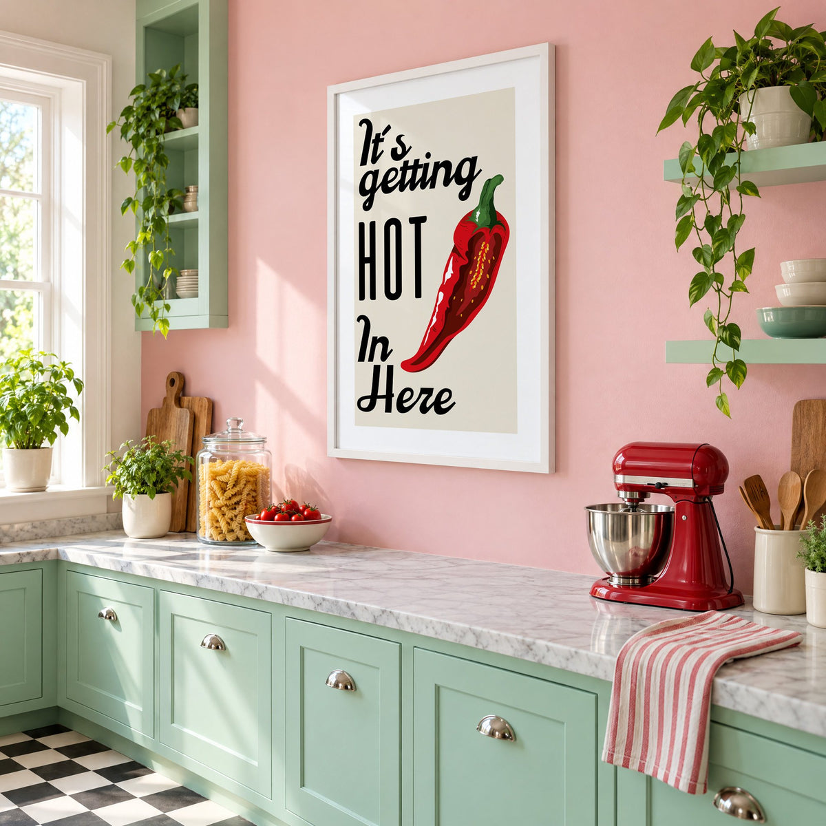 It's getting HOT In Here split chili print in a white frame on a pink wall above mint green cabinets in a retro kitchen, seen at an angle