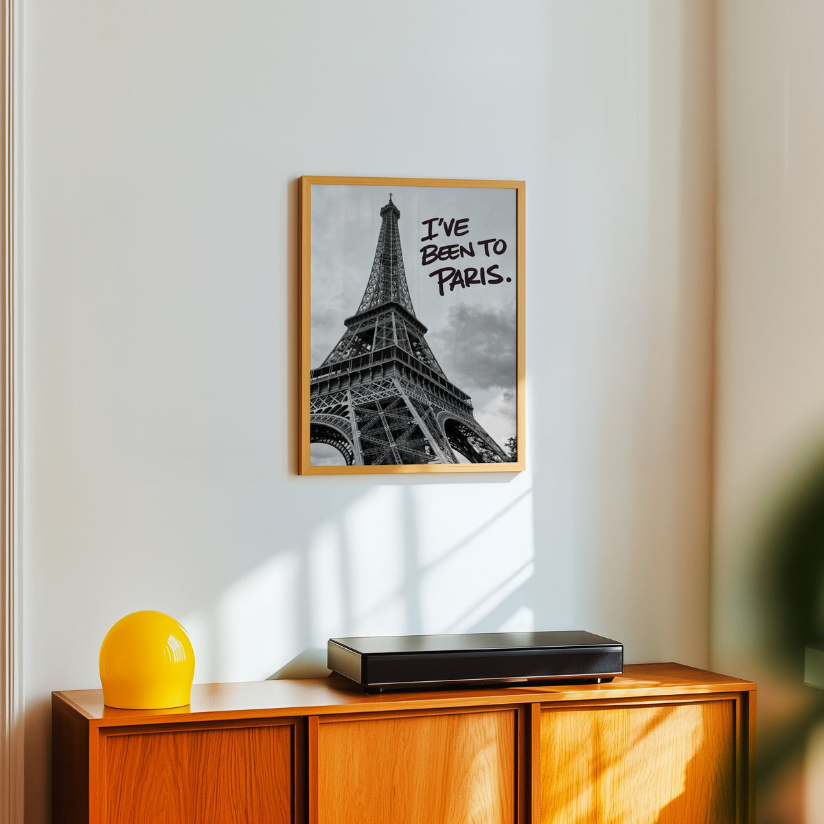 I've Been to Paris handwritten quote on Eiffel photo print in an oak frame above a teak sideboard with a yellow glass lamp