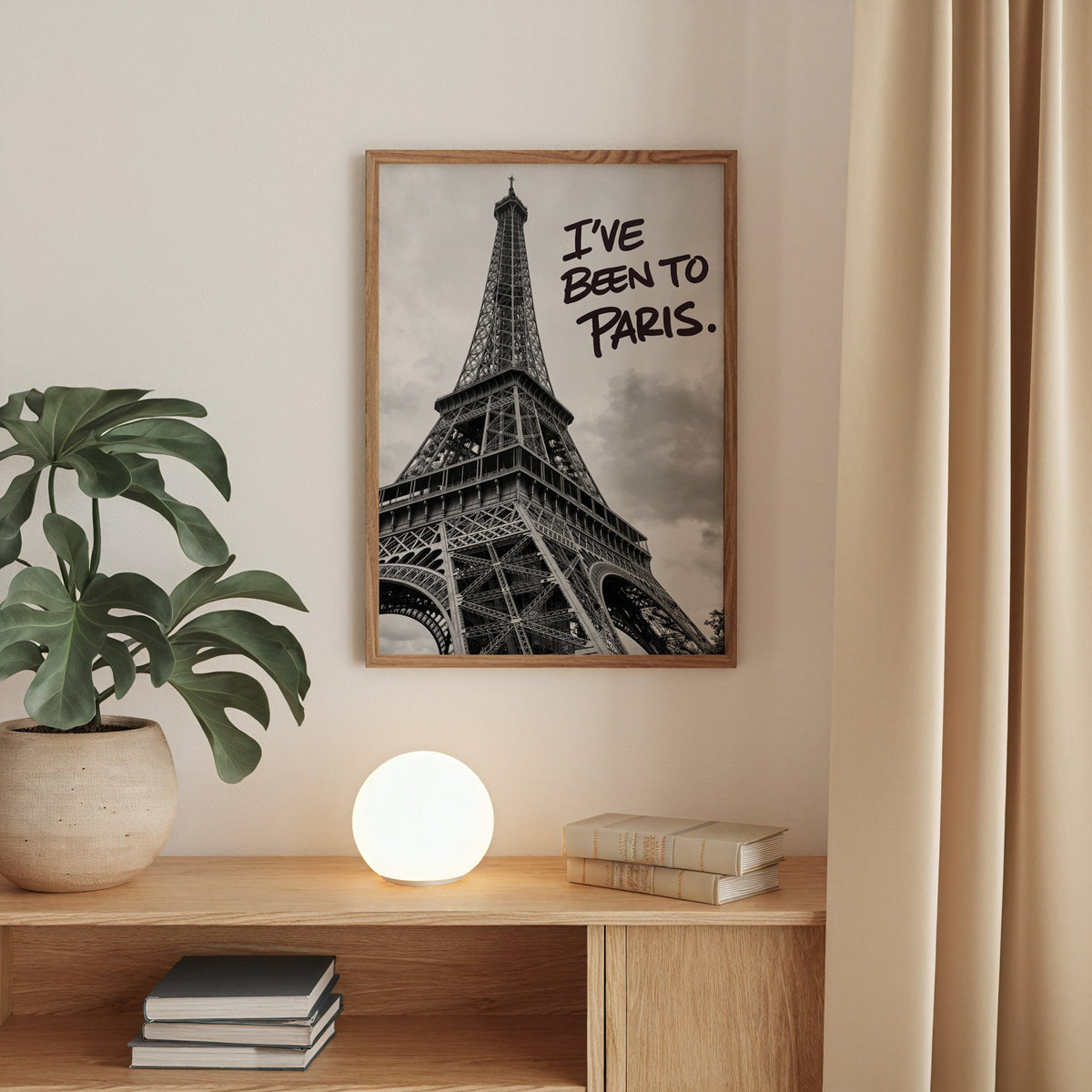 I've Been to Paris handwritten quote on Eiffel photo print in a walnut frame above an oak cabinet with a glowing globe lamp