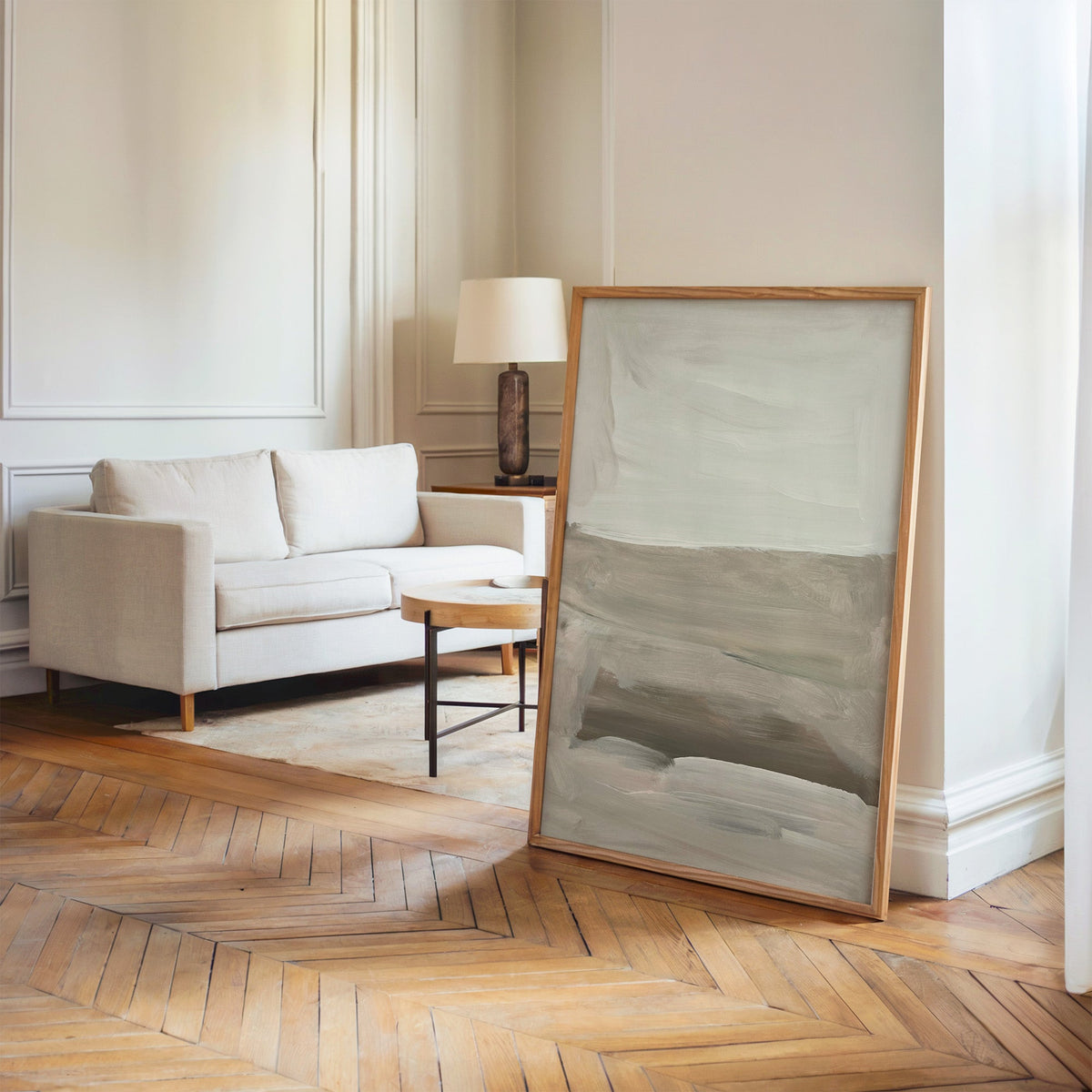 Ivory and taupe soft horizon bands print in an oak frame leaning on a herringbone floor by a cream linen sofa