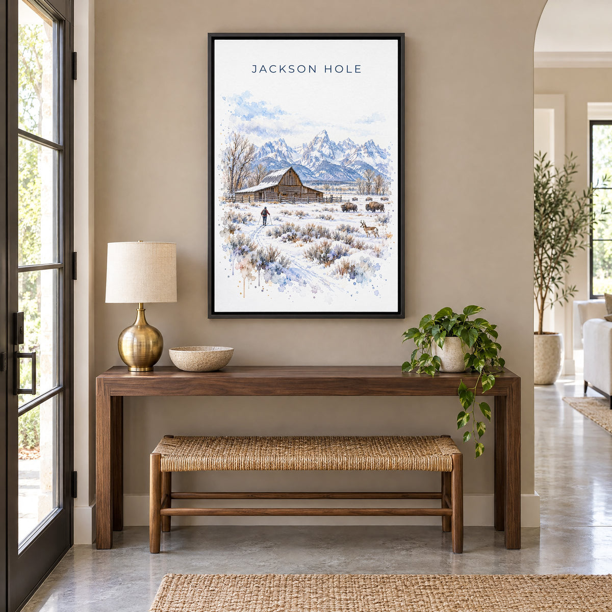 Jackson Hole watercolor print as a black floater canvas above a walnut console and woven bench in an entryway
