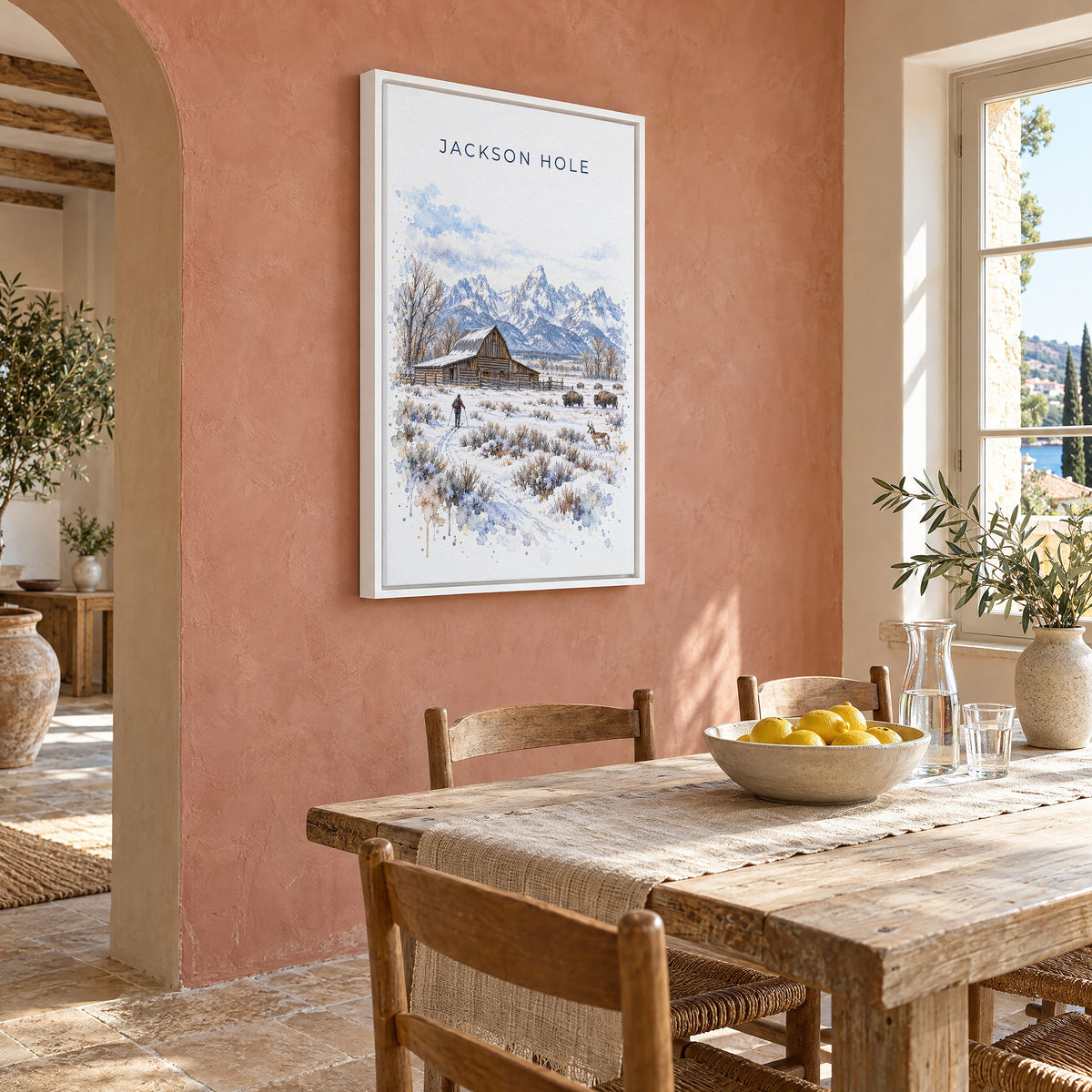 Jackson Hole watercolor print as a white floater canvas on a terracotta wall above a rustic dining table