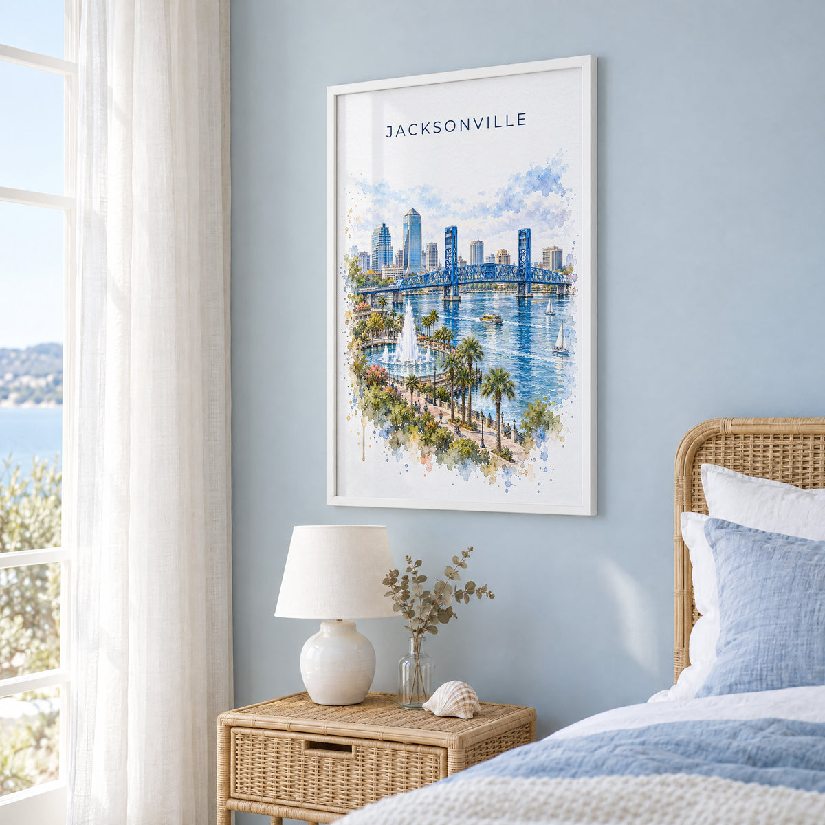 Jacksonville, Florida watercolor print in a white frame on a pale blue wall beside a rattan bed in a coastal bedroom
