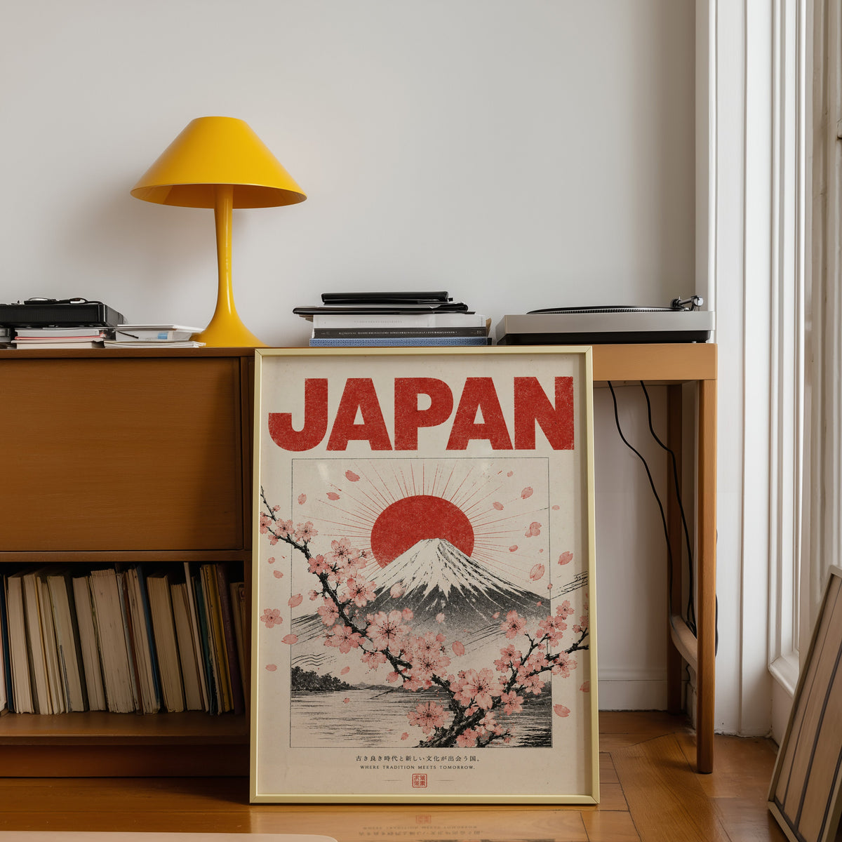 engraved Mount Fuji with sakura print shown in a gold frame leaning under a teak desk with a yellow lamp