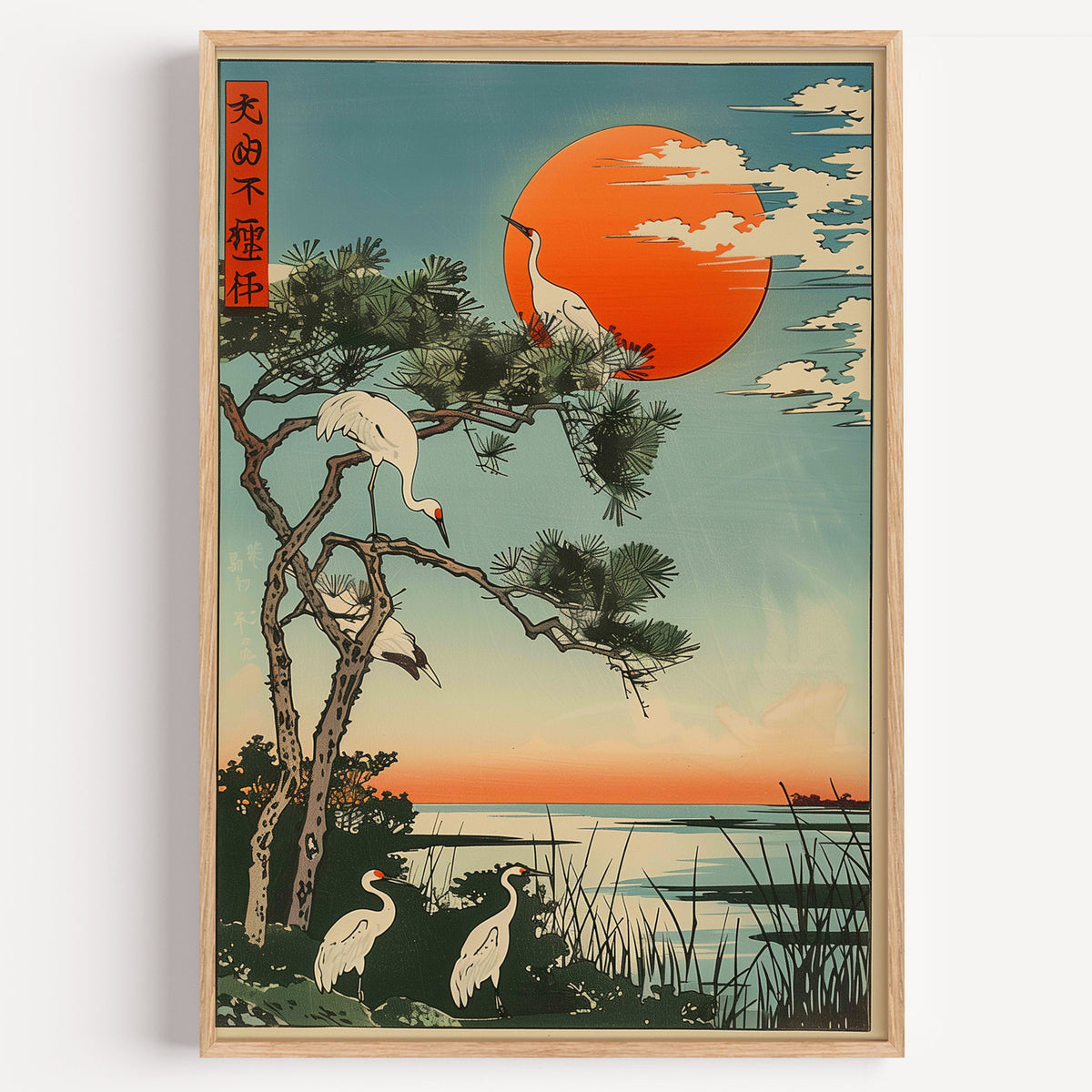Cranes on pine with orange sun print in a light oak frame on a plain white wall