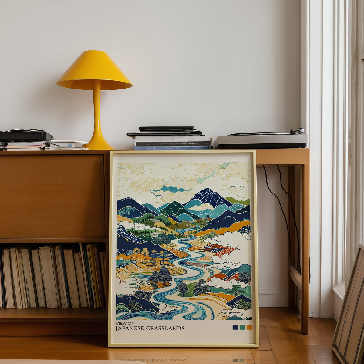 View of Japanese Grasslands river valley print shown in a gold frame below a teak desk with a yellow lamp