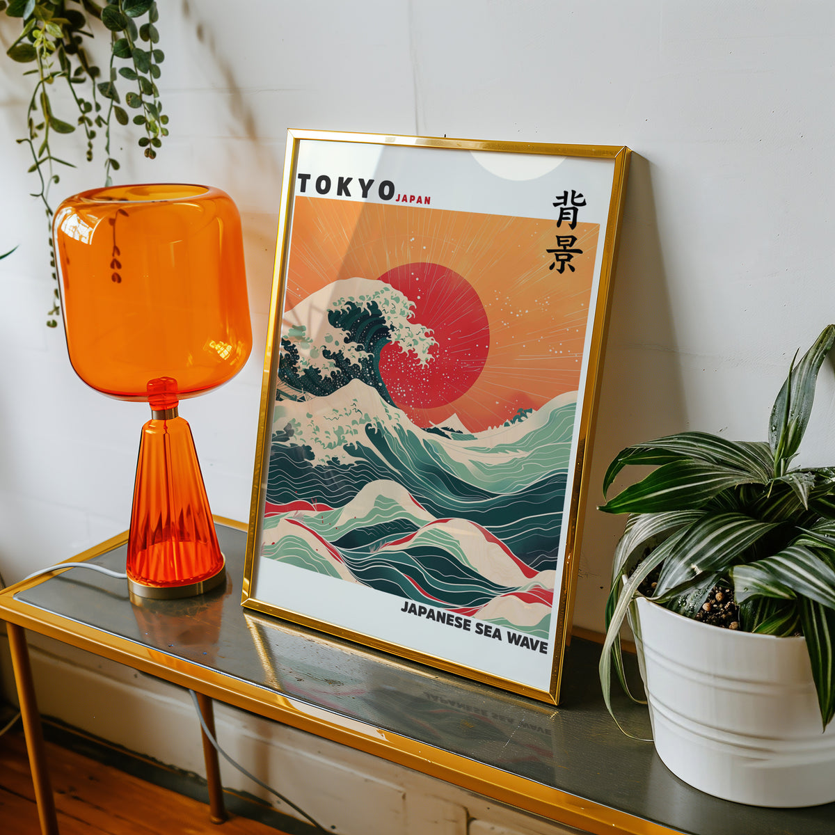 Japanese sea wave red sun print shown in a gold frame on a console beside an orange glass lamp