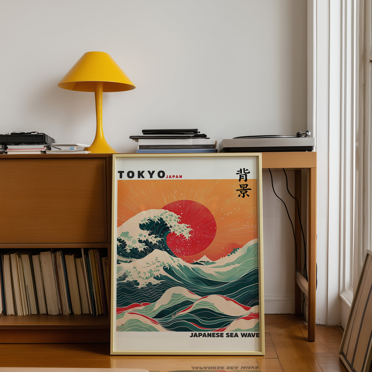 Japanese sea wave red sun print shown in a gold frame below a teak desk with a yellow lamp
