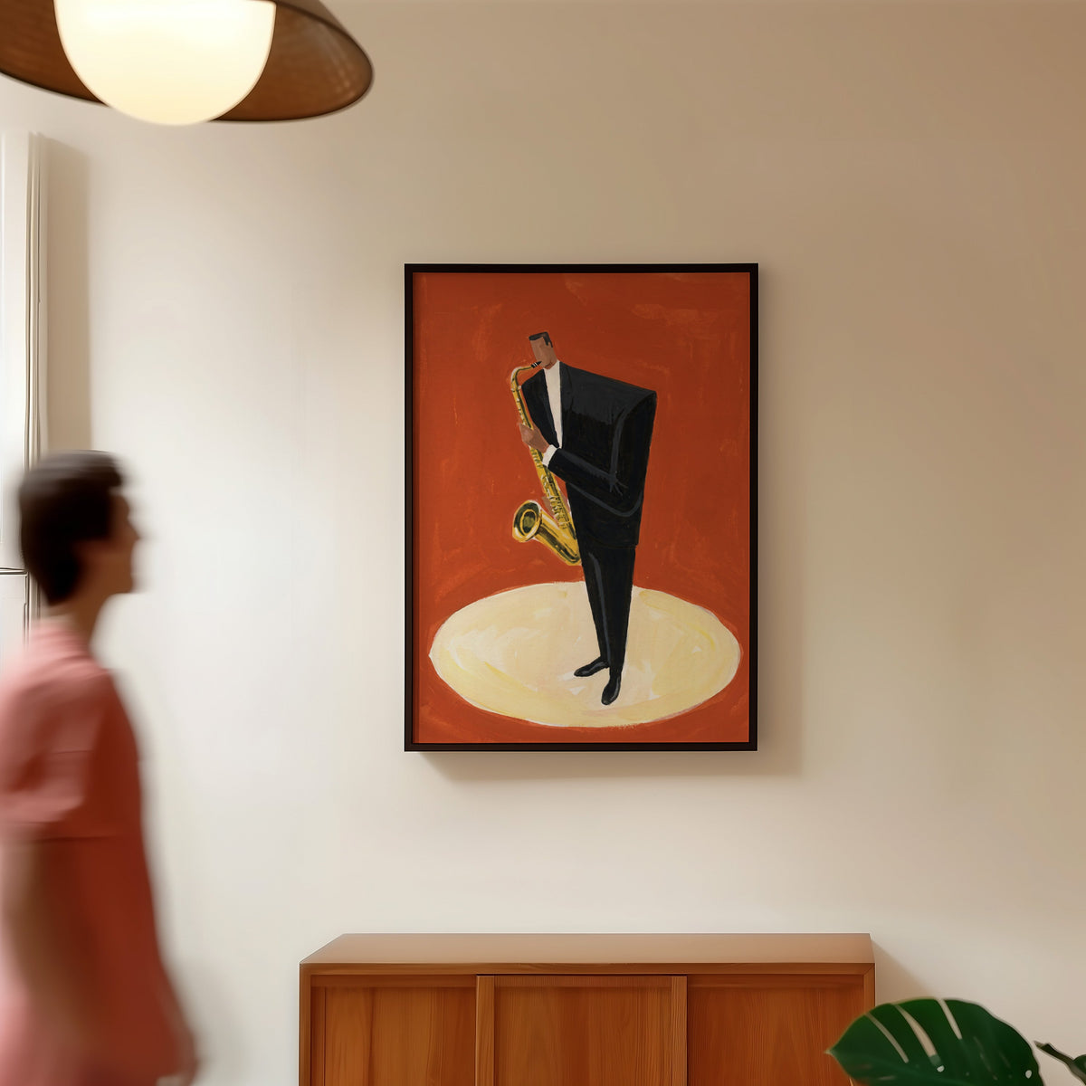 Red jazz club print in a black frame in a hallway under a rattan pendant