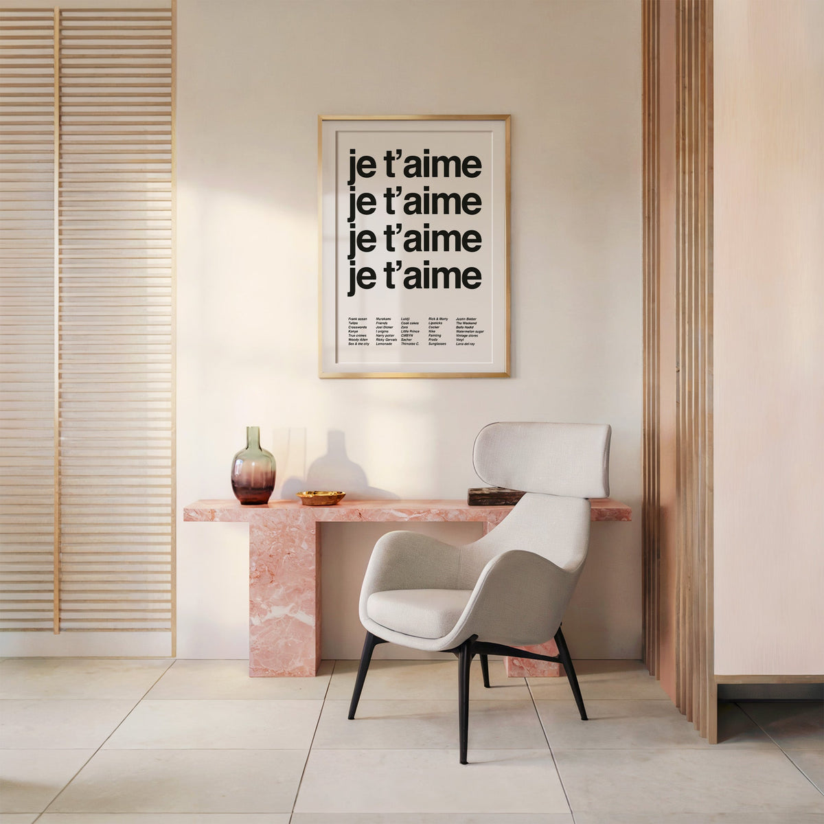 Repeated je t'aime black typography on white print shown in a gold frame above a pink marble console and armchair